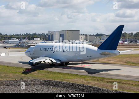 Eine Dreamlifter Taxis in die Position für den Start bei Paine Field in Everett, Washington am 22. August 2019. Die wide-body Cargo Aircraft ist eine modifizierte Boeing 747-400 zum Transport Komponenten der Boeing 787 Dreamliner. In der Ferne sind die Boeing Everett Farbe hangars, wo eine Mehrheit von Boeing wide-body Flugzeuge vor der endgültigen Flight Test bemalt sind. Stockfoto