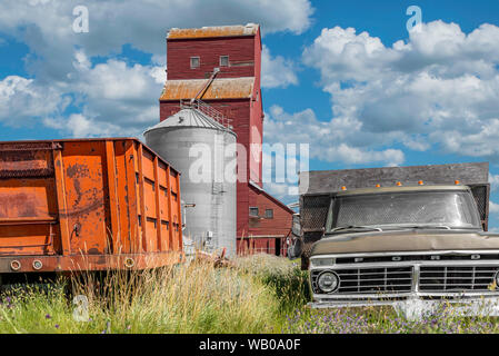 Cadillac, SK/Kanada - 29. Juli 2019: Die historische Cadillac Körnerelevator in Saskatchewan, Kanada, mit zwei alten Lkw im Vordergrund. Stockfoto