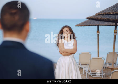 Schönen jungen langhaarigen Braut im weißen Kleid mit ihr junger Ehemann am Strand Stockfoto