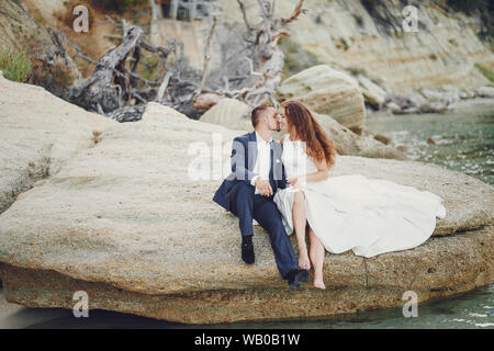 Schönen jungen langhaarigen Braut im weißen Kleid mit ihr junger Ehemann in der Nähe von Fluss Stockfoto