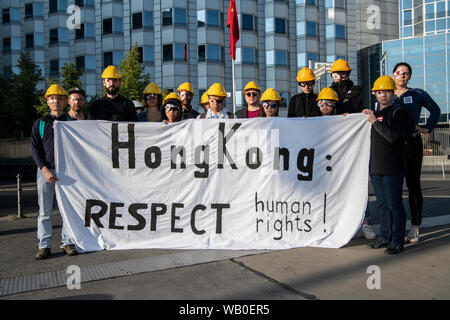 Berlin, Deutschland. 23 Aug, 2019. Demonstranten stand auf eine Mahnwache mit gelben Helm, Schutzbrille und symbolisch fallenden rechten Auge vor der chinesischen Botschaft und fordern Freiheit für Hongkong. In der ehemaligen britischen Kronkolonie Hong Kong es massive Proteste gegen die Regierung seit mehr als zwei Monaten. Die Demonstrationen wurden durch eine Gesetzesvorlage der Regierung mutmaßlichen Straftätern nach China um die Auslieferung von ausgelöst. Credit: Paul Zinken/dpa/Alamy leben Nachrichten Stockfoto