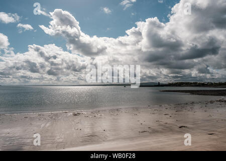 Sonne glitzert auf dem Sandstrand und ruhige See mit Blick auf Carrigaholt Castle im County Clare in Irland Stockfoto