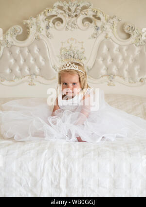 Kleine Prinzessin. Kleines Mädchen tragen tiara Krone und Frisur. Haar  Zubehör. Kleines Kind mit langen blonden Haaren. Kleinen blonden Kind  sitzen auf dem Bett Stockfotografie - Alamy