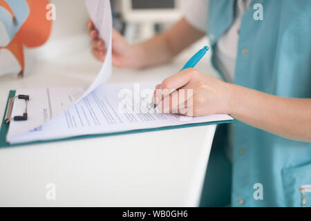 Nahaufnahme von Zahnarzt tragen einheitliche schreiben einige Empfehlungen Stockfoto