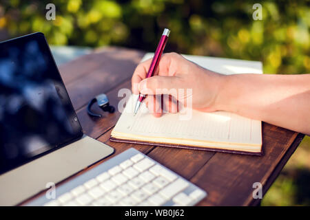 Unternehmer arbeitet mit Laptop und Datensätze in Notebook outdoor Stockfoto