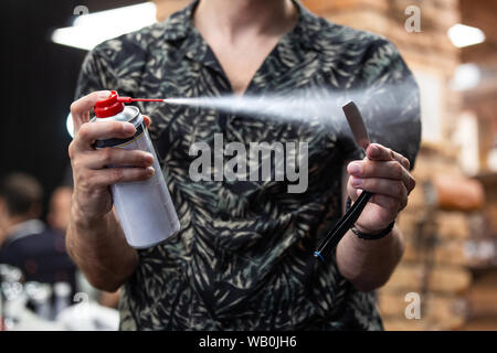 Master Desinfektion rasieren Instrument vor. Junger Mann spray antibakterielle Flüssigkeit auf der Rasierklinge, freien Speicherplatz. Beruf, Schönheit, Barbershop, Pflege Stockfoto