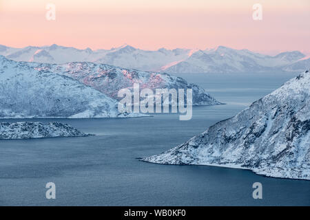 Arktische Landschaft: Fjord und schneebedeckten Bergen mit rot und orange Sunrise, Norwegen Stockfoto