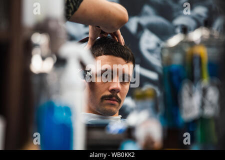 Schuss des Mannes immer trendigen Haarschnitt beim Friseur hautnah. Männliche Friseur servieren Kunden, was Haarschnitt mit Maschine und Kamm. Stockfoto