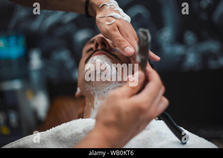 Rasiermesser in der Hand von spezialisierten Friseur. Friseur rasieren ein Mann in einem Friseur, close-up. Mann mith Schnurrbärte in einer Rasur Stockfoto