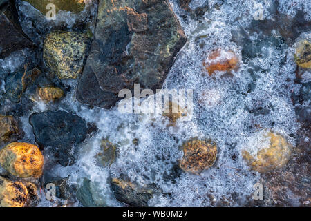 Struktur von Eis und bunte Steine am Strand im Winter; Norwegen Stockfoto