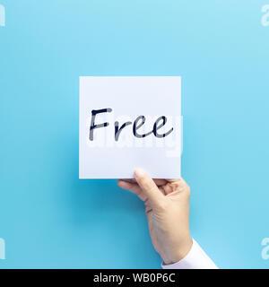 Freies Material für Werbung Konzept. Hand, Papier mit Text auf blauem Hintergrund isoliert, Studio shot Stockfoto