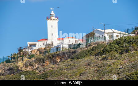 Mossel Bay, Südafrika - an einem klaren Sommertag ein seevogel fliegt über das Kap St. Blaize Leuchtturm auf einem Hügel über der Stadt Bild im Querformat. Stockfoto