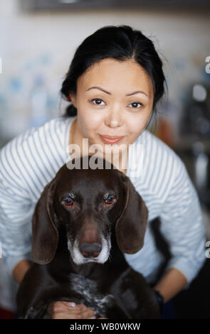 Frau zu Hause ihren Hund umarmt Stockfoto