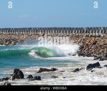 Blaue grüne, glasige Wellen brechen, Rollen sich um und stürzen ab, während sie die Küste im Hafen vor der Bruchmauer von Coffs Harbour erreichen Stockfoto