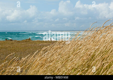 Endlosen weißen Sandstrand mit Düne Gras und Holzzaun in der Bretagne mit atlantischen Wellen am Ufer brechen Stockfoto