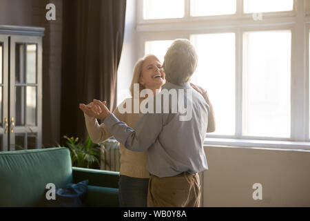 Fröhlicher Rentner Ehegatten lachen Tanzen im Wohnzimmer. Stockfoto