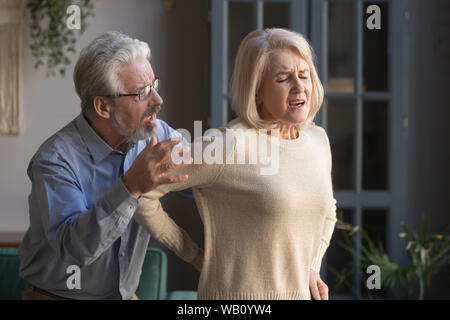 Älterer Mann helfen Frau mittleren Alters plötzlichen Rückenschmerzen fühlen Stockfoto