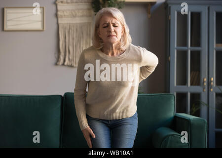 Verärgert alte Frau berühren Wunden Wirbelsäule spüren plötzlich Rückenschmerzen Stockfoto