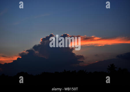 Himmel und dunklen Wolken bei Sonnenuntergang, Horizont begann mit lila Farbe in tropischen Gebieten, Orange, Wolken, die wie riesige Kreatur ist sprühen Feuer Stockfoto