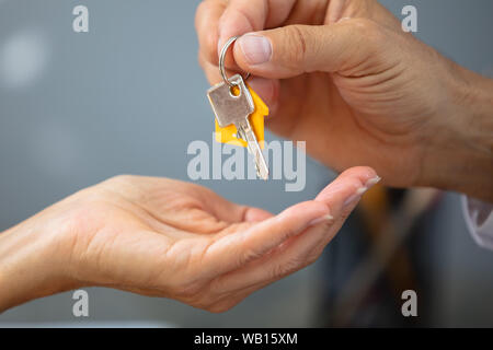 In der Nähe von einem Immobilienmakler Hand geben Haus Schlüssel zu Frau Stockfoto