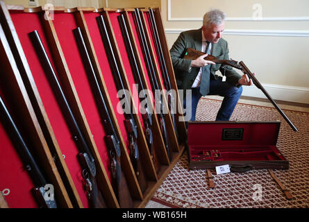 Versteigerer Gavin Gardiner Blick eine feine ken Hunt graviert 12-Bohrung selbst öffnende Sidelock-Schnittstellen ab Auswerfer gun von John Wiles, vor der Gavin Gardiner Ltd jährliche Auktion der Moderne und klassische Sportwaffen in Gleneagles Hotel. Stockfoto