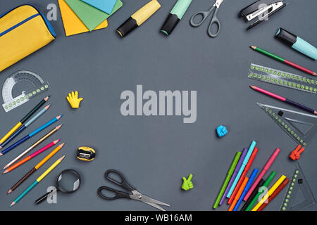 Flach Foto von Arbeitsbereich Schreibtisch mit Schule Zubehör oder Bürobedarf auf grauem Hintergrund. Stockfoto