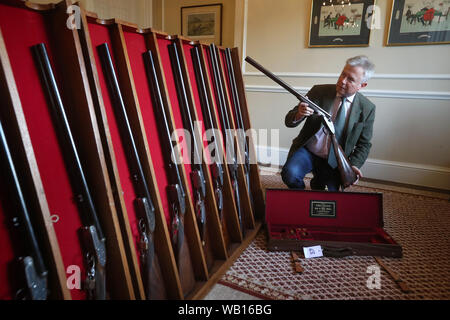 Versteigerer Gavin Gardiner Blick eine feine ken Hunt graviert 12-Bohrung selbst öffnende Sidelock-Schnittstellen ab Auswerfer gun von John Wiles, vor der Gavin Gardiner Ltd jährliche Auktion der Moderne und klassische Sportwaffen in Gleneagles Hotel. Stockfoto