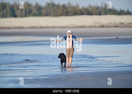 Frau und ihr Hund einen Spaziergang am frühen Morgen entlang Cherry Hill Beach, Nova Scotia, Kanada Stockfoto