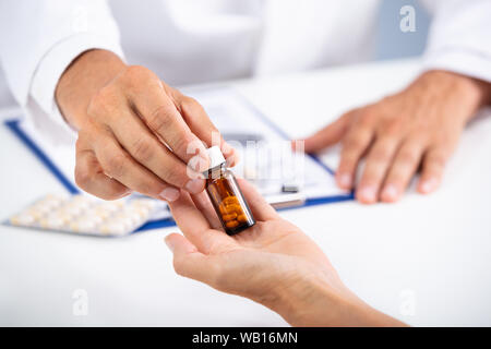 Nahaufnahme der Hand des Arztes, die verschlossene Flasche mit Pillen gefüllt zu Patient Stockfoto