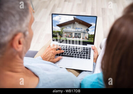 Paar an Haus Online auf Laptop zu Hause Suchen Stockfoto