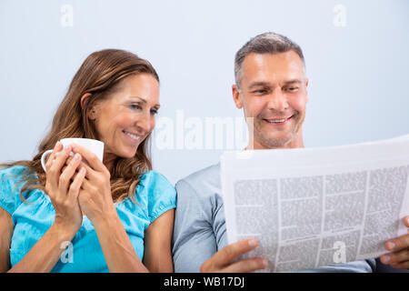 Portrait von Happy Reifes Paar lesen Zeitung zu Hause Stockfoto