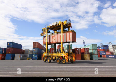 Fahren Straddle Carrier (Van Carrier) mit einem Container im Hafen von Auckland, Neuseeland Stockfoto