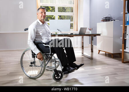 Behinderten Geschäftsmann Sitzen auf Rollstuhl im Büro Stockfoto