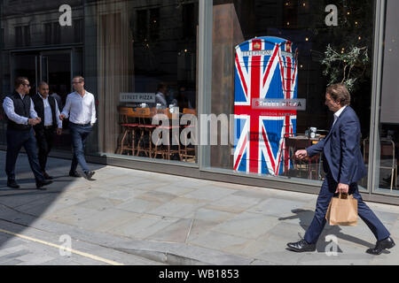 Mittags, die in der City arbeiten, vorbei an den Union Jack - Themen Telefon Kiosk in Starkoch Gordon Ramsay's Restaurant Bread Street Küche auf (der ehemaligen römischen Durchgangsstraße) Watling Street, in der City von London, das Finanzviertel der Hauptstadt (aka der Square Mile), am 22. August 2019, in London, England. Stockfoto