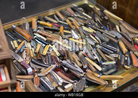 Sammlung von Farbigen und abgenutzte Messer mit Folding Blade verstreut auf dem Tisch. Stockfoto