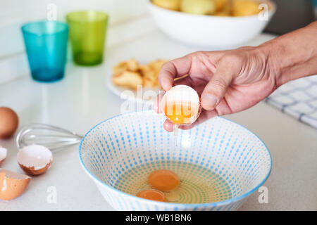 Nahaufnahme von einem kaukasischen Mann in der Küche einige Eier knacken eine typische Tortilla de patatas vorbereiten zu können, ist ein spanisches Omelette, mit Bratkartoffeln gemacht Stockfoto