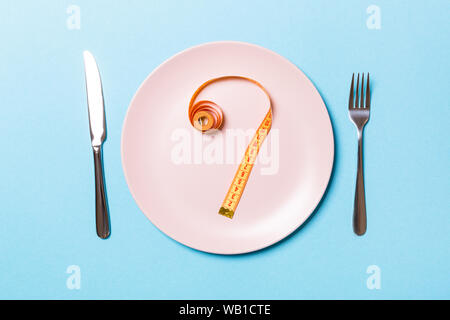 Gabel und Teller mit Maßband auf farbigen Hintergrund. Diät Konzept Stockfoto