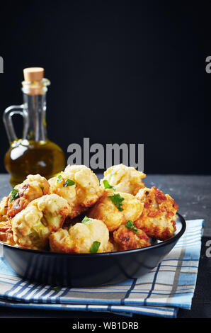 Marokkanische Tempura - Stil gebratenen Blumenkohlröschen in einer Schüssel auf einen konkreten Tisch serviert, vertikale Ansicht, close-up Stockfoto