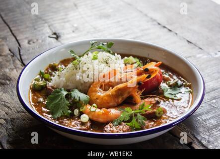 In einer Schüssel auf einer hölzernen Oberfläche Suppe mit Garnelen, Reis und Gemüseblättern schließen Stockfoto