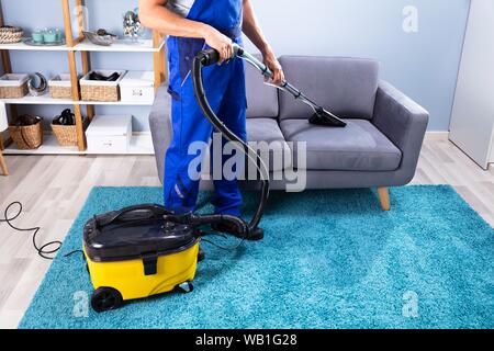 Foto der Person Reinigung Sofa mit Staubsauger Stockfoto