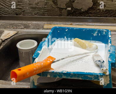 Kleine Bürstenrolle, Pinsel, Farbe und sonstigen Werkzeugen während Wandfarbe funktioniert Stockfoto