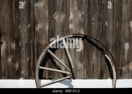 Broken wagon wheel gegen eine Wand. Spocott Windmühle Dorf, Cambridge, MD, USA Stockfoto