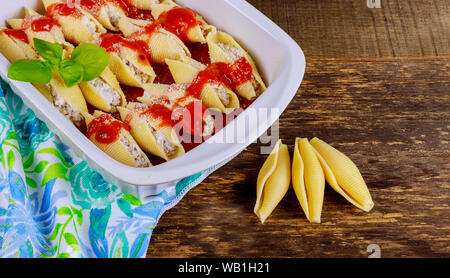 Pasta Muscheln gefüllt mit Käse und Champignons, mit Parmesan bestreut, in Auflaufform. Stockfoto