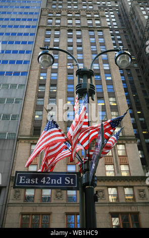 US flags an Straßenlaternen außerhalb der Blöcke auf die 42nd Street, Manhattan, New York City. Stockfoto