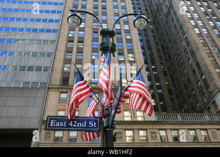 US flags an Straßenlaternen außerhalb der Blöcke auf die 42nd Street, Manhattan, New York City. Stockfoto