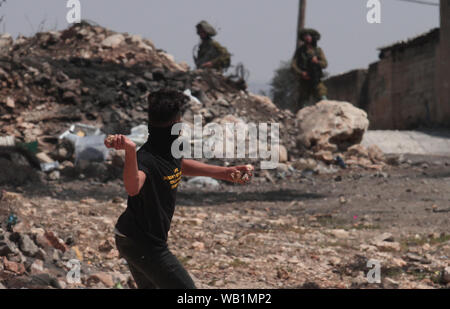 Nablus, Palästina. 23 Aug, 2019. Eine palästinensische Demonstranten schleudert Steine auf israelische Soldaten bei Auseinandersetzungen, nach einem Protest gegen den Ausbau jüdischer Siedlungen in Kufr Qadoom Dorf in der Nähe der Stadt Nablus im Westjordanland, 23.08.2019. Quelle: Xinhua/Alamy leben Nachrichten Stockfoto