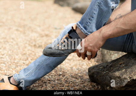 Junge setzen auf seine kletterschuhe in ein Platz im Freien Stockfoto