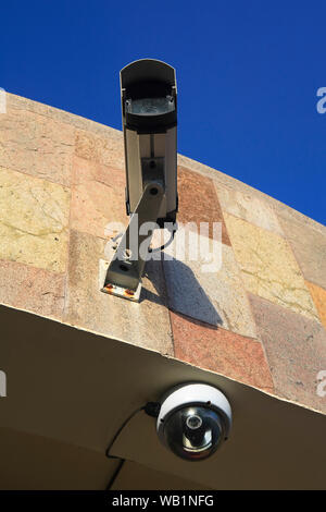 CCTV-Kamera an der Außenwand eines Gebäudes, vor blauem Himmel. Stockfoto