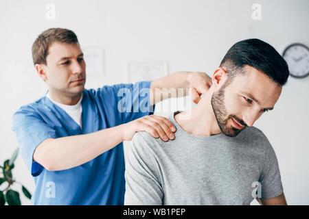 Selektiver Fokus der Patient sitzt auf der Couch und Doktor massieren Patienten Hals in massage Cabinet an der Klinik Stockfoto