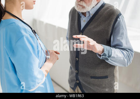 7/8-Ansicht der pensionierte Mann Gestik, und im Gespräch mit der Krankenschwester Stockfoto